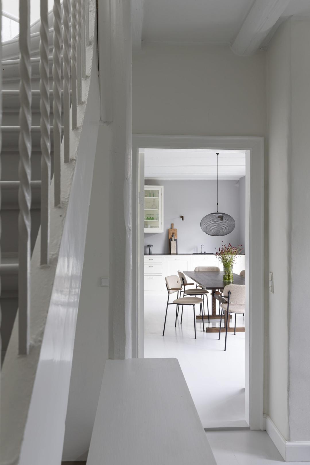 Udsigt fra trappen mod køkkenet, et lyst, minimalistisk interiør i nordisk stil.