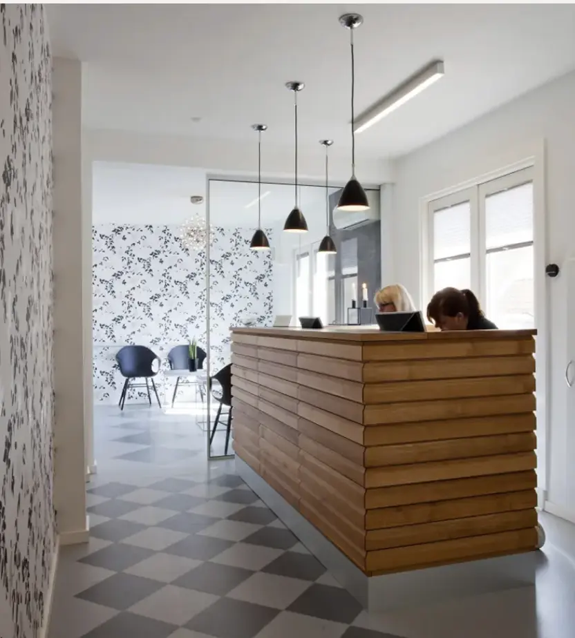 En receptionsdisk i træ, omgivet af et minimalistisk hvidt interiør, kombinerer elegance og naturlighed