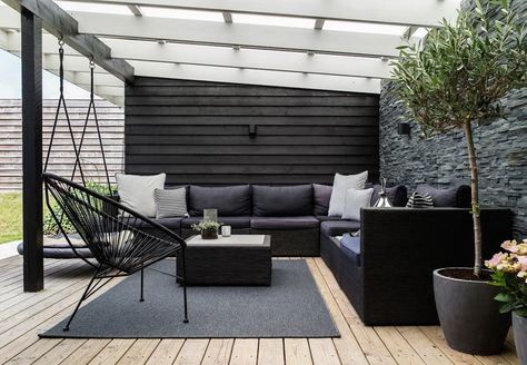 Overdækket terrasse med mørke møbler og sort gulvtæppe